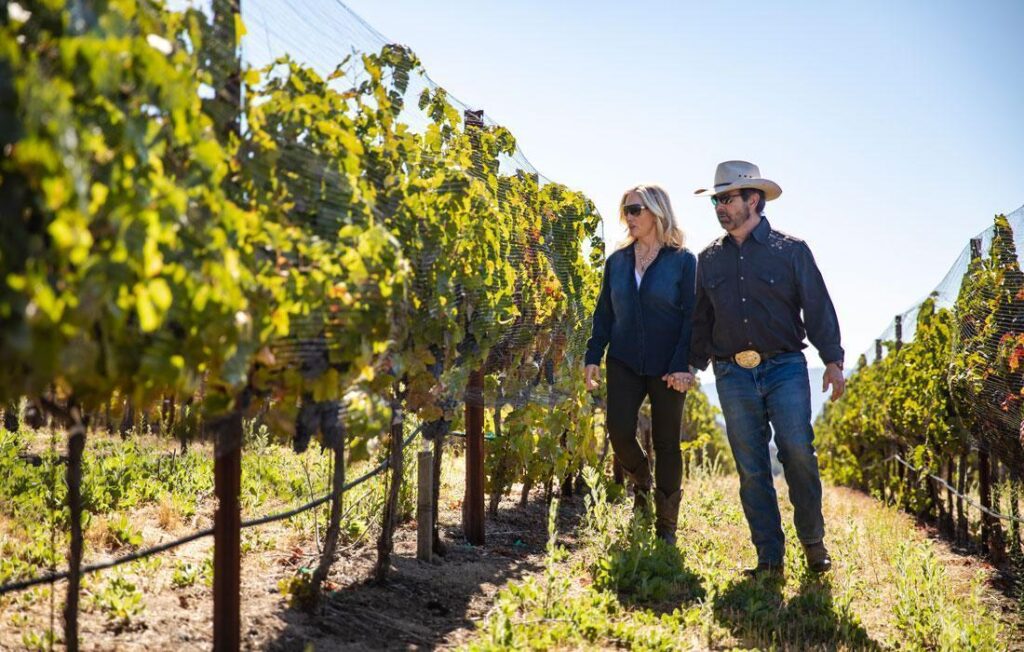 Man and woman walk through their grape vineyard in California financed with an AgFi farm loan.