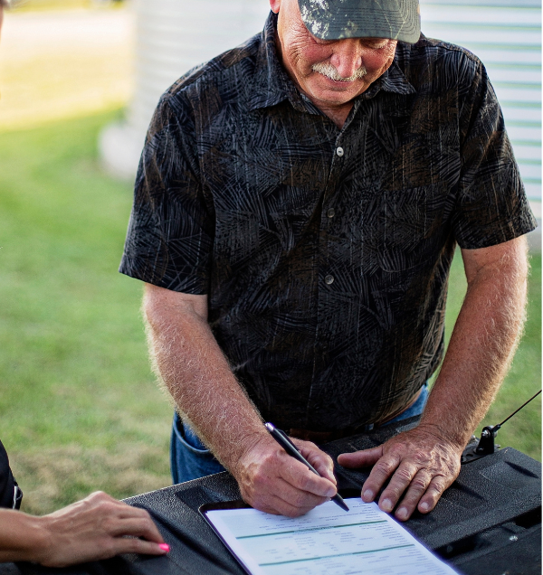 Man Works to Calculate His Loan Payment While Working on Farm Loan Application with Sales Officer
